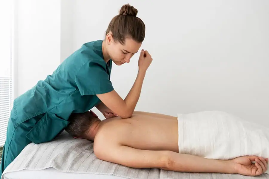 A therapist applying deep pressure with the elbow during a myofascial release massage to relieve muscle tightness and improve flexibility.