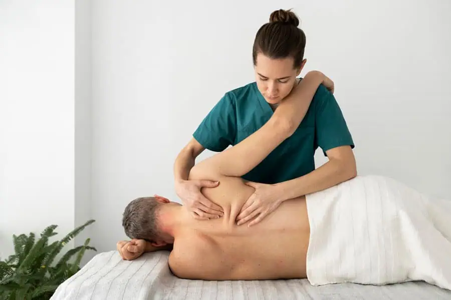Massage therapist performing myofascial release technique on client's upper back in Tampa
